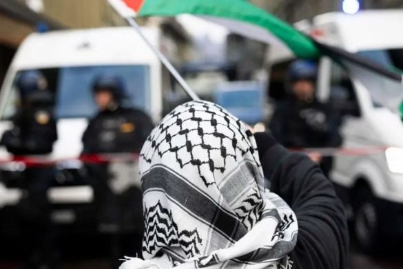 Prosvjednik s kefijom i palestinskom zastavom suočava se s policijom tijekom nedozvoljenog pro-palestinskog skupa u Bernu, 11. listopada 2025.