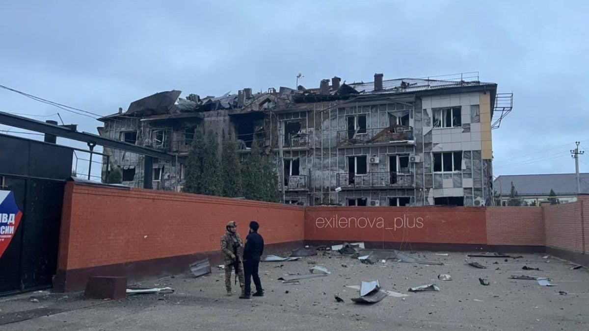 Oštećena zgrada vojne baze Ahmata u Gudermesu nakon napada, s pripadnicima sigurnosti ispred ruševina.