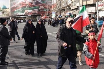 Iranski građani prolaze pokraj velikog patriotskog transparenta s iranskom zastavom na trgu Enghelab u Teheranu tijekom masovnih prosvjeda.