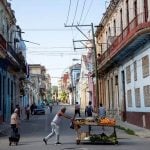 Ulica u Havani s oronulim zgradama i prodavačem voća na kolicima