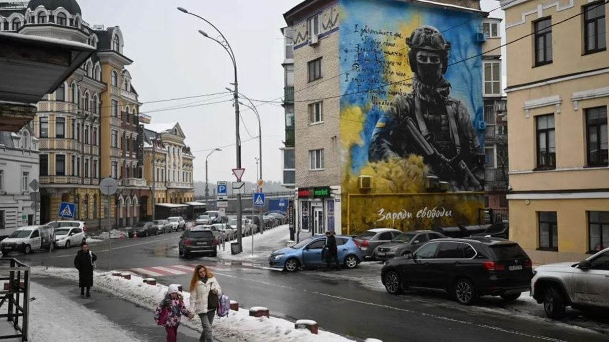 Pješaci prolaze pokraj stambene zgrade s domoljubnim muralom ukrajinskog vojnika u Kijevu tijekom ruske invazije na Ukrajinu, 28. siječnja 2026.