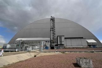 Zaposlenici prolaze ispred Novog sigurnog omotača koji prekriva uništeni četvrti reaktor u Černobilu.