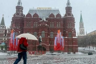 Osoba s kišobranom hoda ispred Kremlja tijekom snježne oluje u Moskvi.